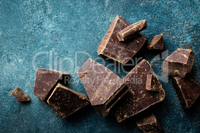 Dark chocolate pieces crushed on a dark background, view from above