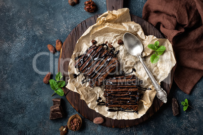 Chocolate brownie cake, dessert with nuts on dark background, directly above, flat lay