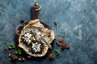 Chocolate brownie cake, dessert with nuts on dark background, directly above, copy space, flat lay