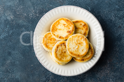 Frying homemade cottage cheese pancakes, syrniki on white plate