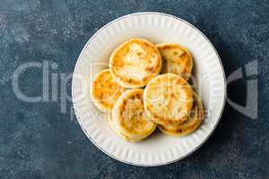 Frying homemade cottage cheese pancakes, syrniki on white plate