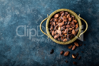 Cocoa beans on dark background, top view, copy space, flat lay