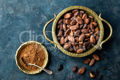 Cocoa beans and powder on dark background, top view, copy space, flat lay