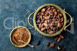 Cocoa beans and powder on dark background, top view, copy space, flat lay