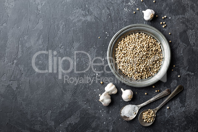 White pepper, garlic and salt on dark grey culinary background, various spices, directly above, flat lay, copy space