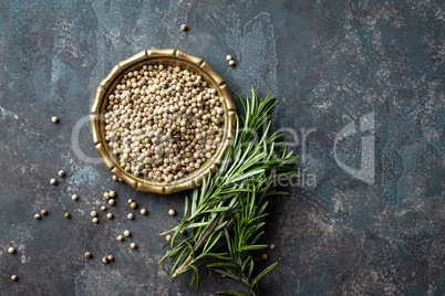 White pepper and fresh rosemary twigs, culinary ingredients on dark background, copy space
