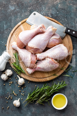 Raw uncooked chicken legs, drumsticks on wooden board, meat with ingredients for cooking, top view