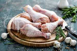 Raw uncooked chicken legs, drumsticks on wooden board, meat with ingredients for cooking