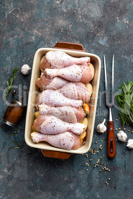 Raw uncooked chicken legs, drumsticks on wooden board, meat with ingredients for cooking, top view