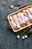 Raw uncooked chicken legs, drumsticks on wooden board, meat with ingredients for cooking, top view