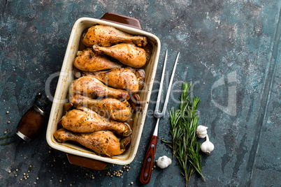 Grilled fried roast chicken legs, drumsticks on dark background, meat with ingredients for cooking, top view