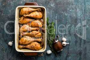 Grilled fried roast chicken legs, drumsticks on dark background, meat with ingredients for cooking, top view
