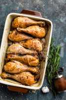 Grilled fried roast chicken legs, drumsticks on dark background, meat with ingredients for cooking, top view