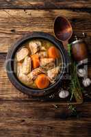 Meat stewed with carrots in sauce and spices in cast iron pot on dark wooden rustic background