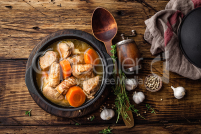Meat stewed with carrots in sauce and spices in cast iron pot on dark wooden rustic background