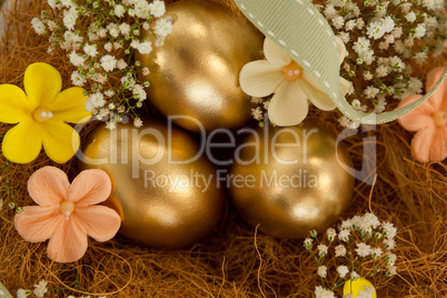 Golden easter eggs with flowers in nest