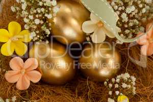 Golden easter eggs with flowers in nest