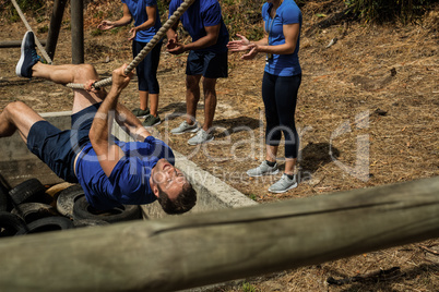 Man crossing the rope during obstacle course while people cheering him