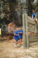 Fit men climbing a wooden wall during obstacle course