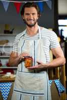 Smiling shop assistant holding a jar of pickle