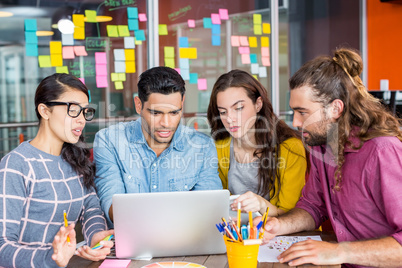 Smiling graphic designers discussing over laptop in meeting