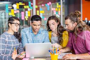 Smiling graphic designers discussing over laptop in meeting