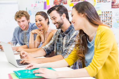 Smiling executives discussing over laptop