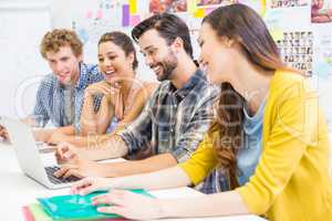 Smiling executives discussing over laptop