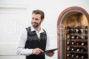 Male waiter smiling while using digital tablet