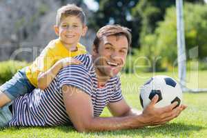 Father and son lying on grass in the park on a sunny day