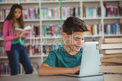 Schoolboy using laptop in library