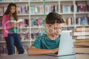Schoolboy using laptop in library