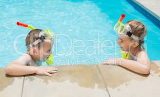 Boy and girl relaxing on the side of swimming pool