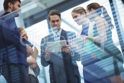 Business executives using electronic devices in corridor