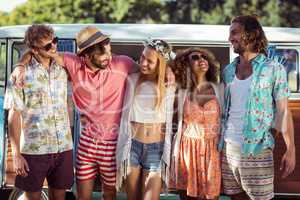 Group of happy friends standing together near campervan