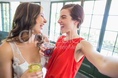 Friends taking a selfie while holding cocktail glasses