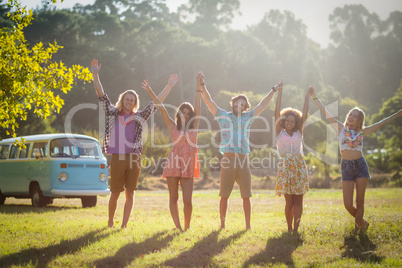 Friends raising their hands in park