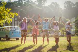 Friends raising their hands in park