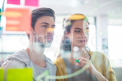Two executives reading sticky notes on glass wall