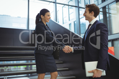 Business executives shaking hands on stairs
