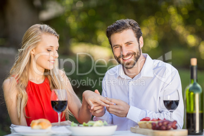 Man putting a ring on womans finger in the restaurant