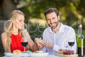 Man putting a ring on womans finger in the restaurant