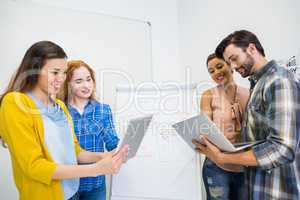 Smiling executives discussing over digital tablet and laptop in conference room meeting
