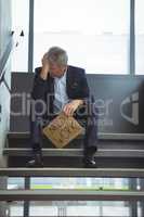 Depressed businessman sitting on stairs holding cardboard sheet with text need work
