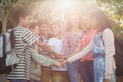 Happy school kids forming hand stack in campus