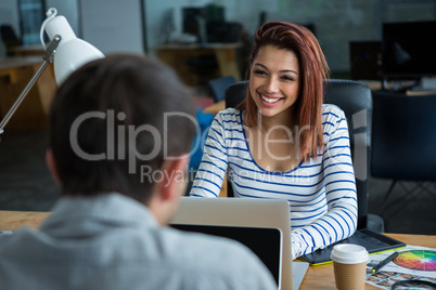 Man and woman sitting at desk and interacting each other