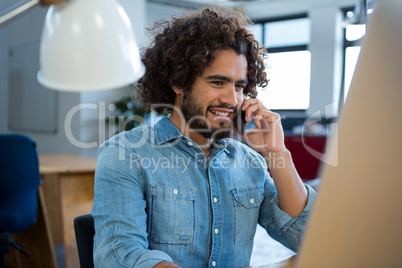 Smiling graphic designer talking on mobile phone