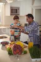 Father and son preparing smoothie in kitchen