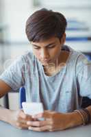 Schoolboy using mobile phone in classroom