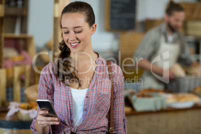 Smiling woman using mobile phone at counter